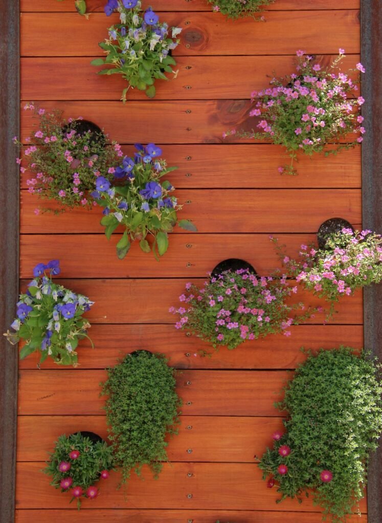 Vertical garden with vibrant flowers on red wooden planks, enhancing home decor.